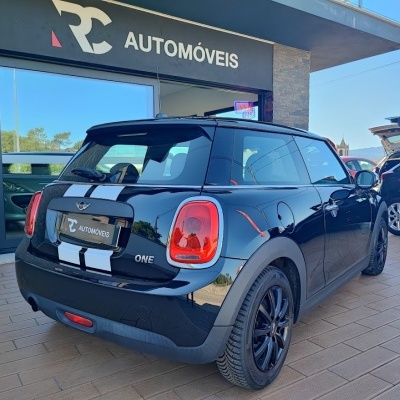 Mini Cooper One preto com riscas brancas na traseira, estacionado frente a loja RC AUTOMÓVEIS