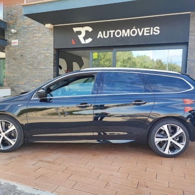 Carro preto metálico tipo carrinha ao lado de loja RC Automóveis