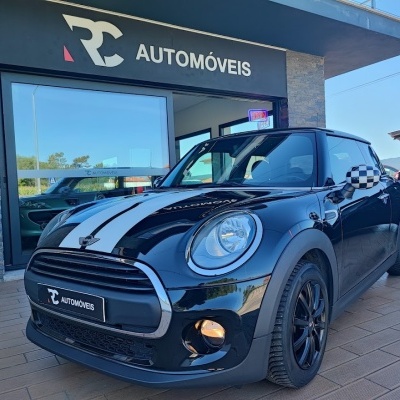 Mini Cooper preto com riscas brancas e espelhos xadrez em frente a loja RC AUTOMÓVEIS
