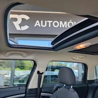 Interior de carro com teto solar aberto e janela lateral com vista para loja RC AUTOMÓVEIS