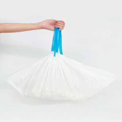 Saco branco com alças azuis segurado por uma mão