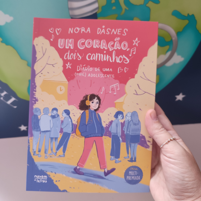 Um coração, dois caminhos | Booksmile Livro 'Um Coração, Dois Caminhos' com ilustração de personagem juvenil e pessoas ao fundo