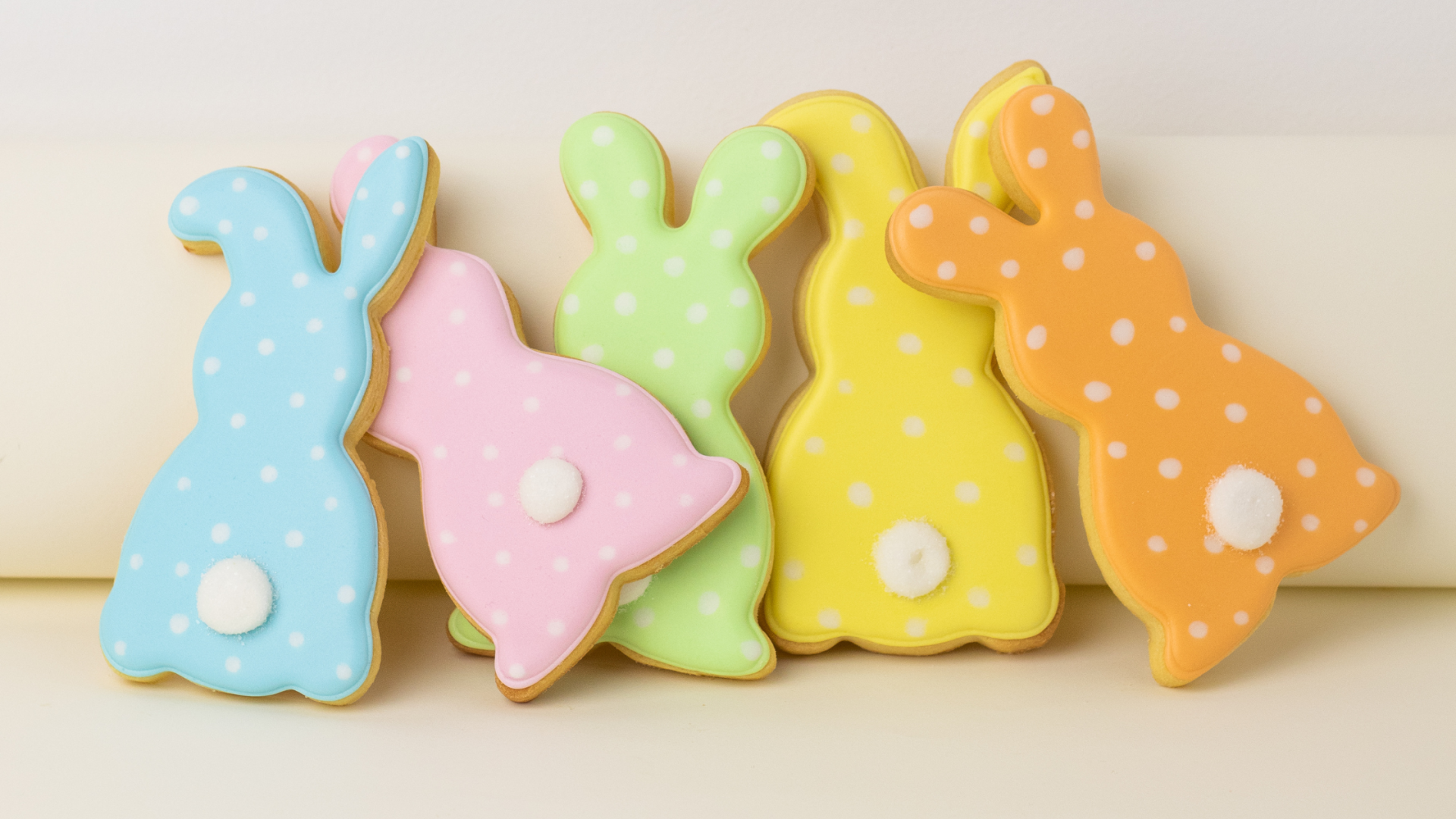 Biscoitos decorados em forma de coelhos e campainha coloridos com glacê e bolinhas brancas