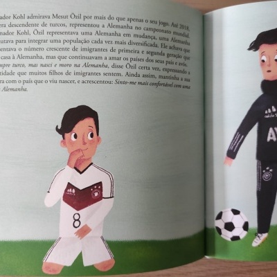 Ilustração de duas crianças em uniforme de futebol com texto em português num livro infantil aberto