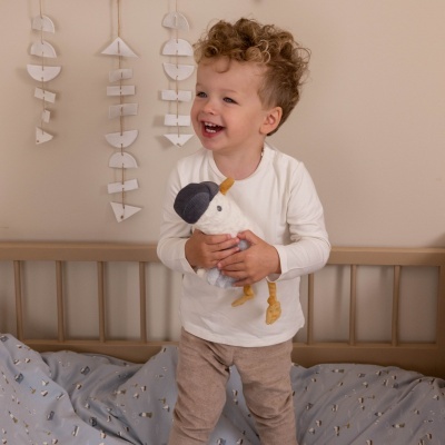 Criança sorridente com brinquedo de pelúcia em quarto infantil