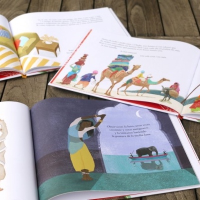 Livros infantis abertos com ilustrações coloridas sobre uma mesa de madeira