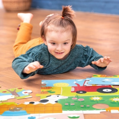 Criança a montar puzzle grande colorido no chão