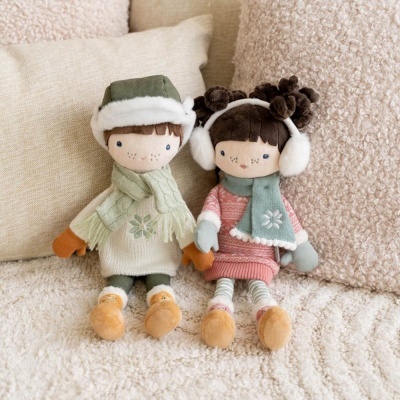 Dois bonecos de peluche vestidos com roupas de inverno sentados num sofá creme