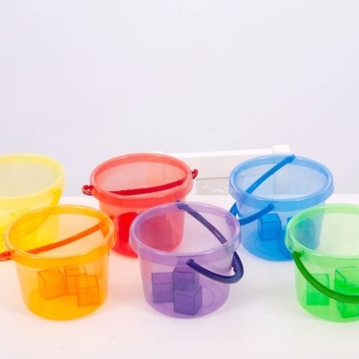 Seis baldes de plástico coloridos e translúcidos com alças, sobre superfície branca
