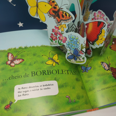Página de livro infantil com ilustrações 3D de borboletas coloridas sobre relva verde e texto em português