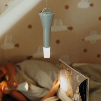 Lanterna LED portátil cinza pendurada com luz acesa num quarto com papel de parede de nuvens.