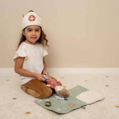 Criança a brincar no chão com tapete verde e acessórios de médico em tecido.