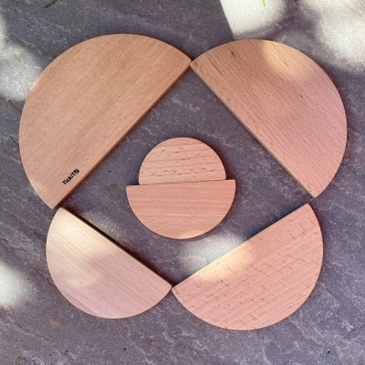 Peças de madeira clara geométricas sobre fundo cinzento com sombras