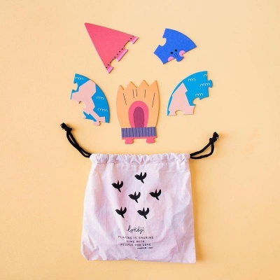 Peças de puzzle de madeira coloridas sobre saco branco com texto em fundo amarelo