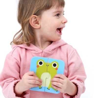 Criança com puzzle de rã em fundo branco