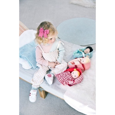 Criança com bonecas em cama com mantas