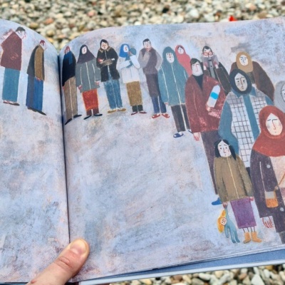 Livro ilustrado aberto com várias figuras humanas vestidas com roupas de inverno coloridas