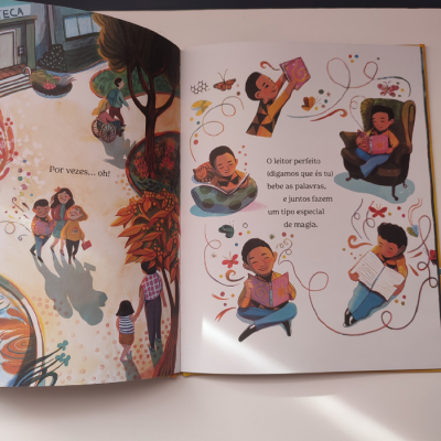 Livro infantil aberto com ilustrações de crianças a ler e brincar