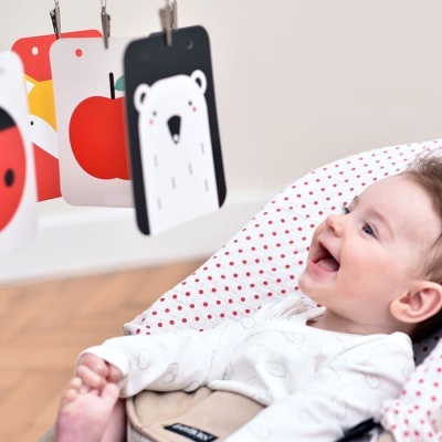 Bebé no assento olhando para cartões coloridos pendurados