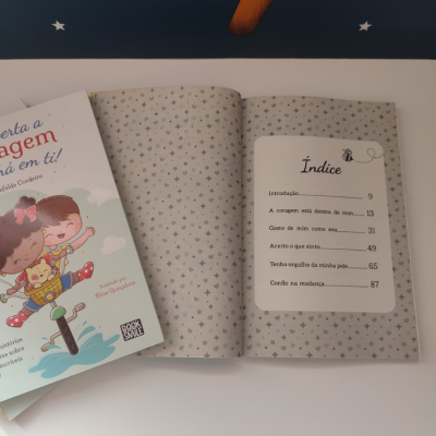Dois livros infantis, um fechado com capa ilustrada e outro aberto com índice e padrão de estrelas cinza