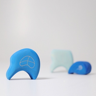Três brinquedos de madeira azuis com formas curvas sobre superfície branca