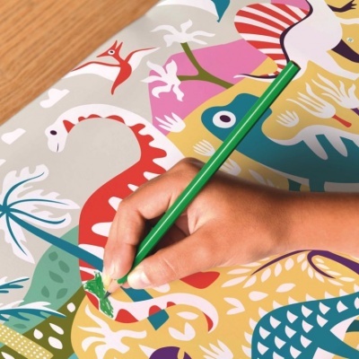 Livro de colorir de dinossauros com mão a usar lápis verde