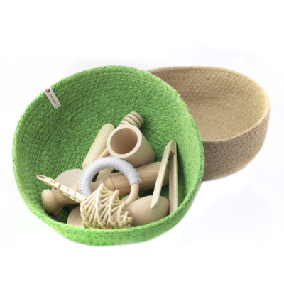 Dois cestos pequenos, um verde e outro bege, com utensílios de madeira no interior do cesto verde.