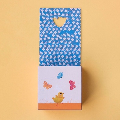 Caixa de papel para presente azul com flores brancas e coração recortado, pintinho amarelo e borboletas coloridas