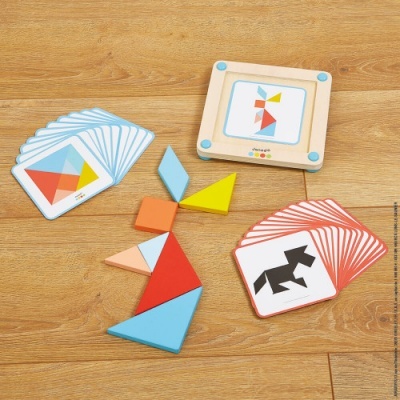 Jogo de tangram infantil com peças coloridas e cartas ilustrativas num piso de madeira