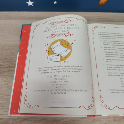 Páginas abertas de livro Natal com instruções para escrever carta ao Pai Natal, em fundo de estrelas brancas sobre azul.