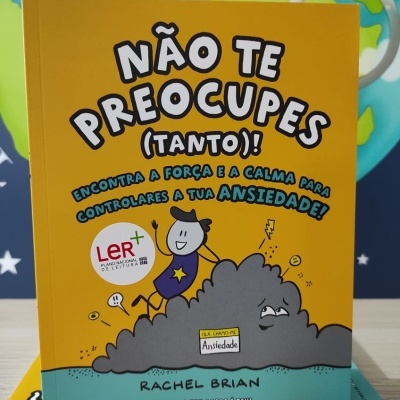 Capa de livro amarelo e azul com título 'NÃO TE PREOCUPES (TANTO)!' e ilustração de personagem sobre nuvem cinzenta