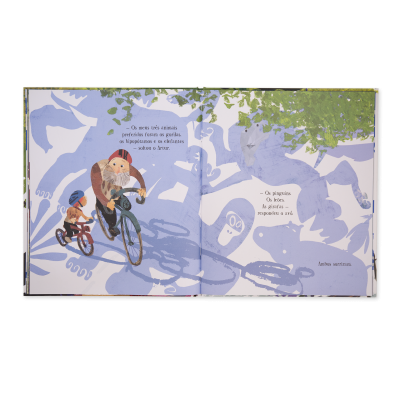 Livro infantil aberto com ilustrações de crianças a andar de bicicleta e texto em português