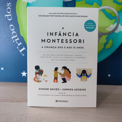 Capa de livro branco com título e ilustrações coloridas de crianças sobre mesa de madeira