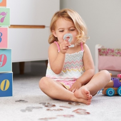 Menina pequena a brincar com blocos numéricos e comboio de madeira
