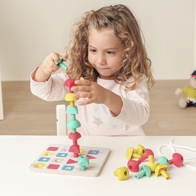 Criança a brincar com brinquedo educativo de madeira colorido.