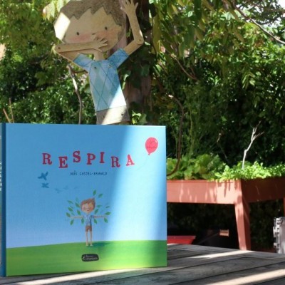 Livro infantil RESPIRA em ambiente de jardim com mesas e cadeiras