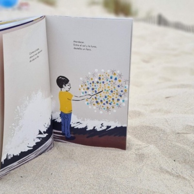 Livro infantil aberto na areia com ilustração colorida e texto em inglês