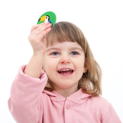 Criança com casaco rosa segurando ficha verde com desenho de tucano