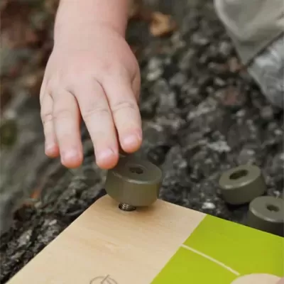 Mão infantil a colocar peça redonda cinza em tabuleiro de madeira