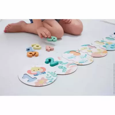 Jogo educativo com números em madeira e bases ilustradas no chão e criança a jogar