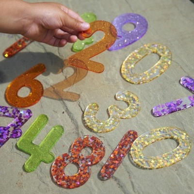Números decorativos coloridos com brilhos sobre uma superfície de madeira clara