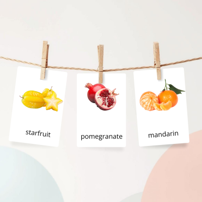 Cartões com imagens de starfruit, romã e mandarina pendurados numa corda com molas de madeira