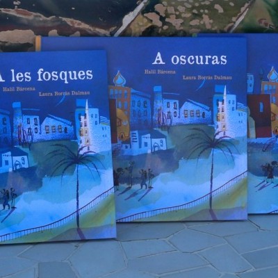 Três livros com capas azuis sobre um chão de pedra, cada um com uma ilustração noturna e textos em línguas diferentes.