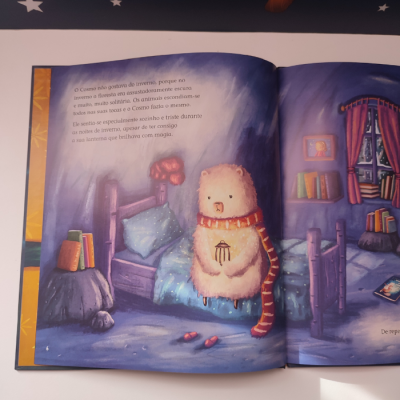 Livro infantil aberto com urso sentado na cama e texto em português