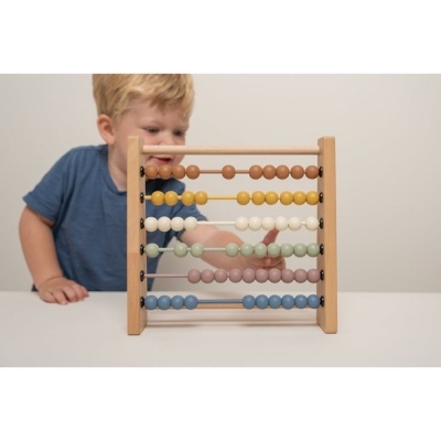 Menino com ábaco de madeira colorido numa mesa branca