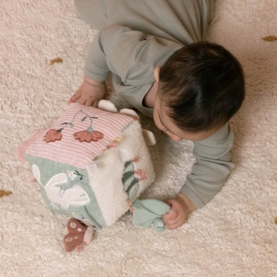 Bebé a brincar com cubo de tecido colorido sobre tapete felpudo bege