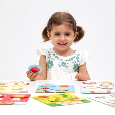 Menina a brincar com puzzles de madeira coloridos