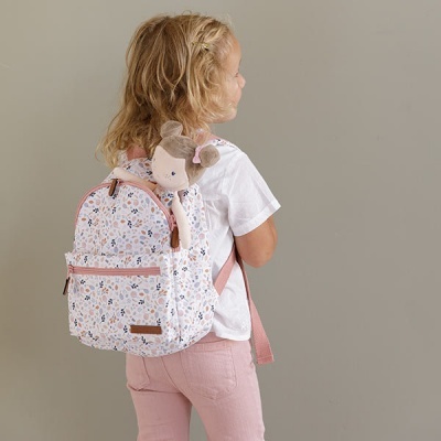 Criança de costas com mochila floral rosa e boneca de tecido