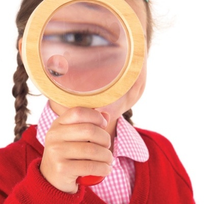 Menina segurando lupa de madeira que amplia seu olho