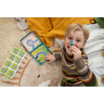 Criança a brincar com jogo de tabuleiro em caixa de plástico azul e transparente.